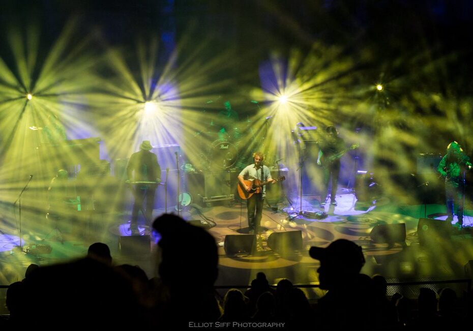 Band performing on stage with colorful lights.