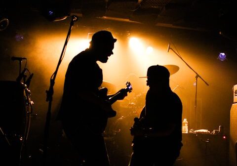 Silhouetted musicians performing on stage with lighting.