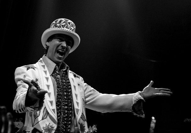 Performer in ornate suit and hat gesturing.