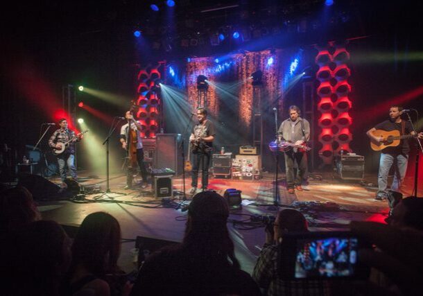 Band performing on stage with colorful lights.