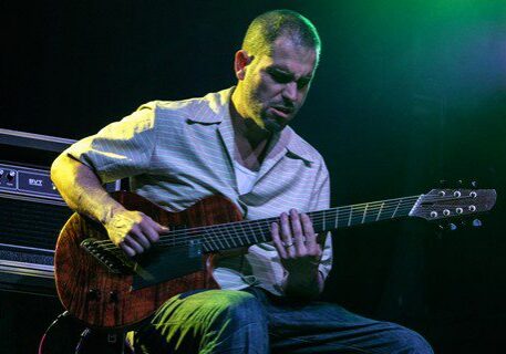Guitarist playing on stage with amplifier.