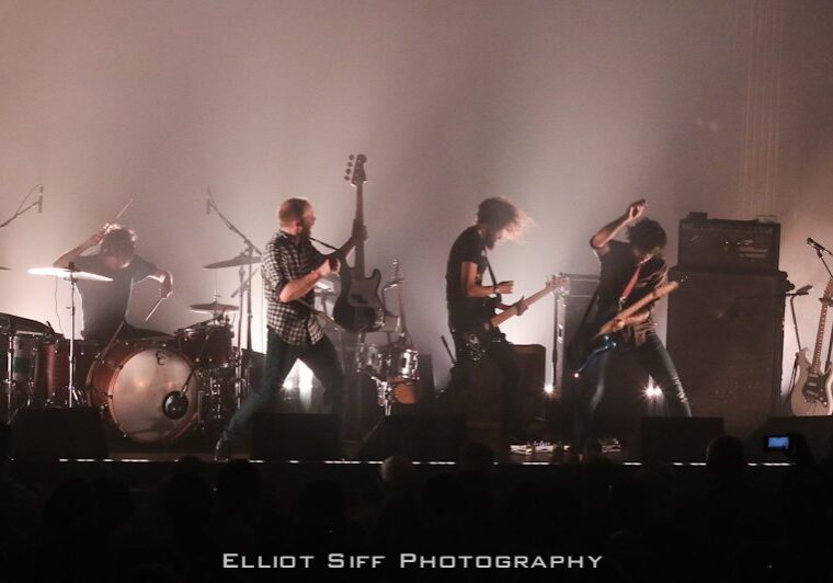 Rock band performing energetically on stage.