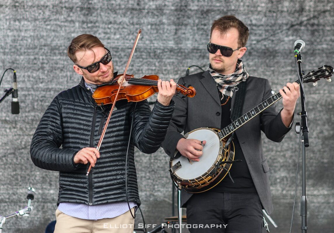 Musicians playing violin and banjo on stage.