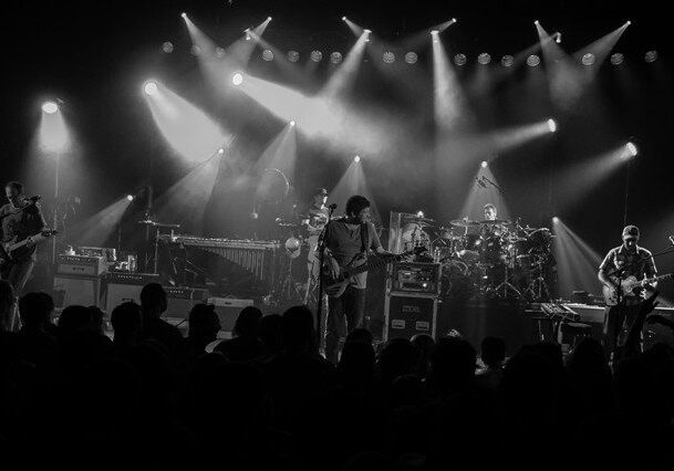 Band performing on stage with bright lights.