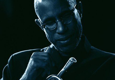 Musician holding trumpet in dim lighting.
