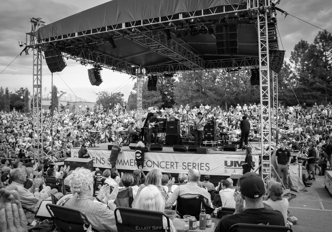 Outdoor concert with large seated audience.