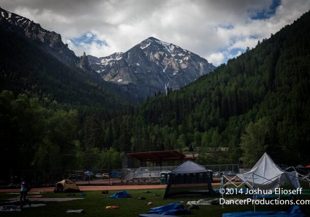 Mountain campsite with tents and cloudy sky.