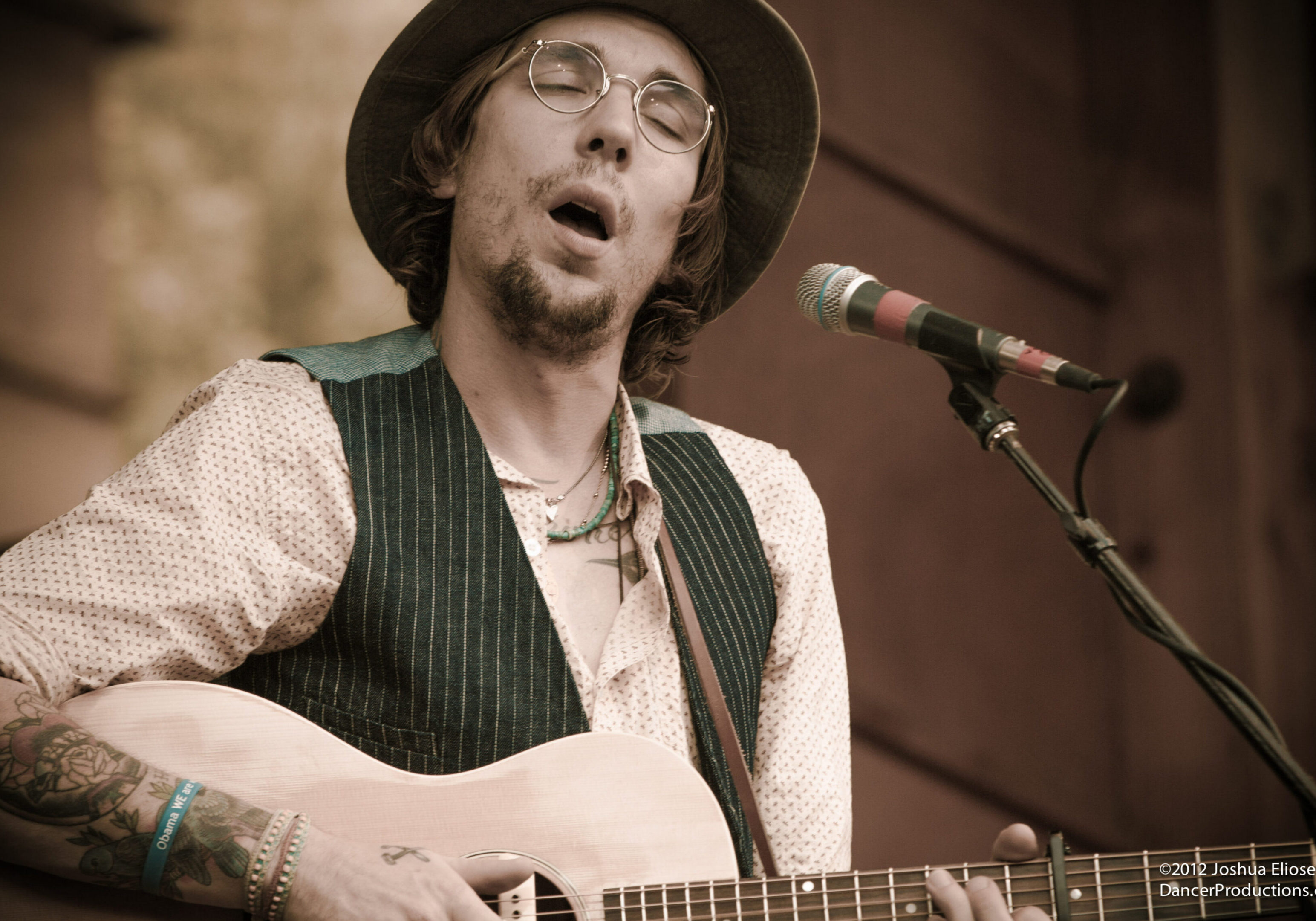 Musician playing guitar and singing passionately.