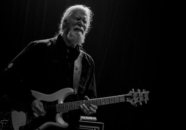 Guitarist performing passionately on stage.