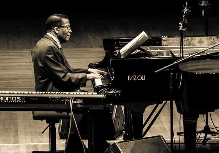 Man playing piano on stage, black-and-white.