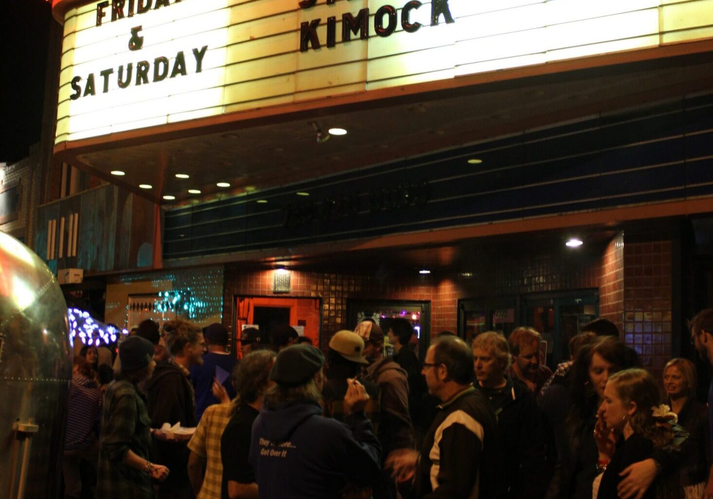 Crowd outside venue with event marquee.