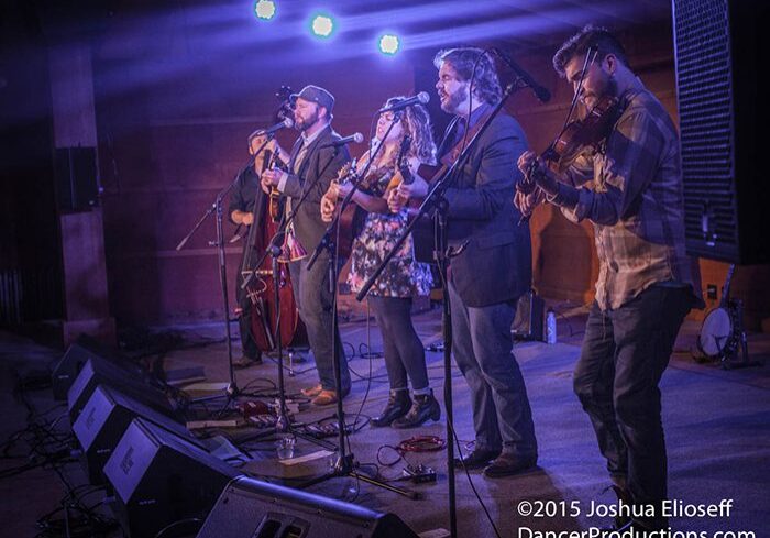 Band performing live on stage with instruments.