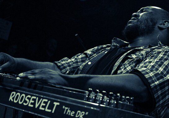 Man playing musical instrument passionately on stage.
