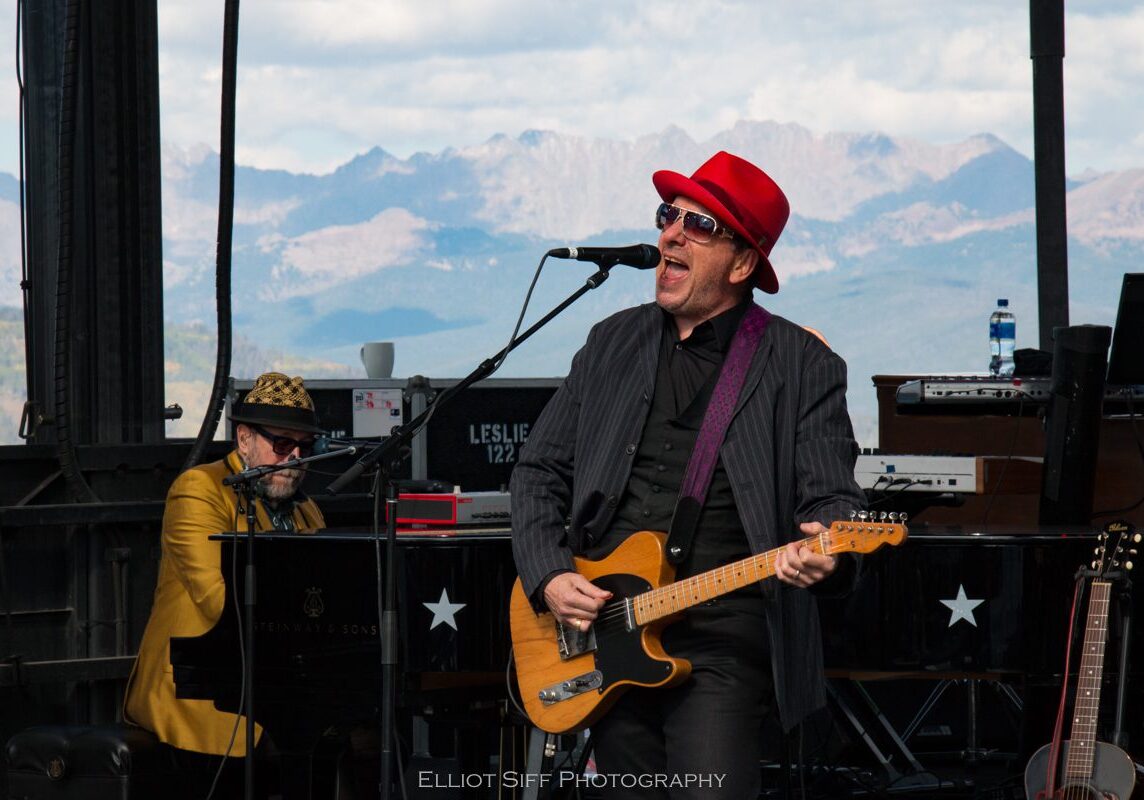 Musician performing on stage with guitarist.