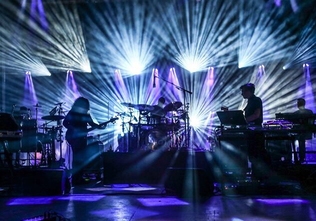 Band performing on stage with vibrant lights.