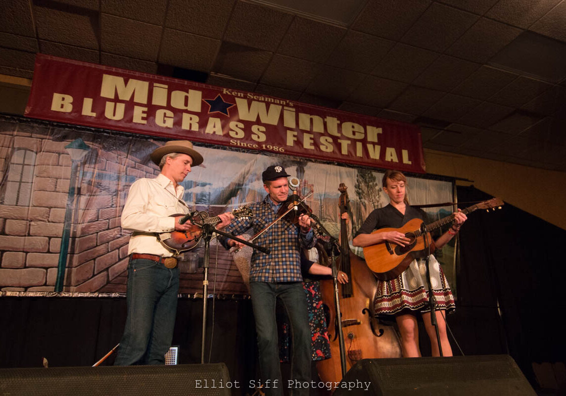 Musicians performing at bluegrass festival stage.