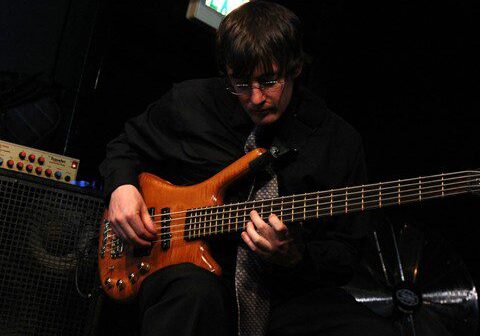 Musician playing bass guitar on stage.
