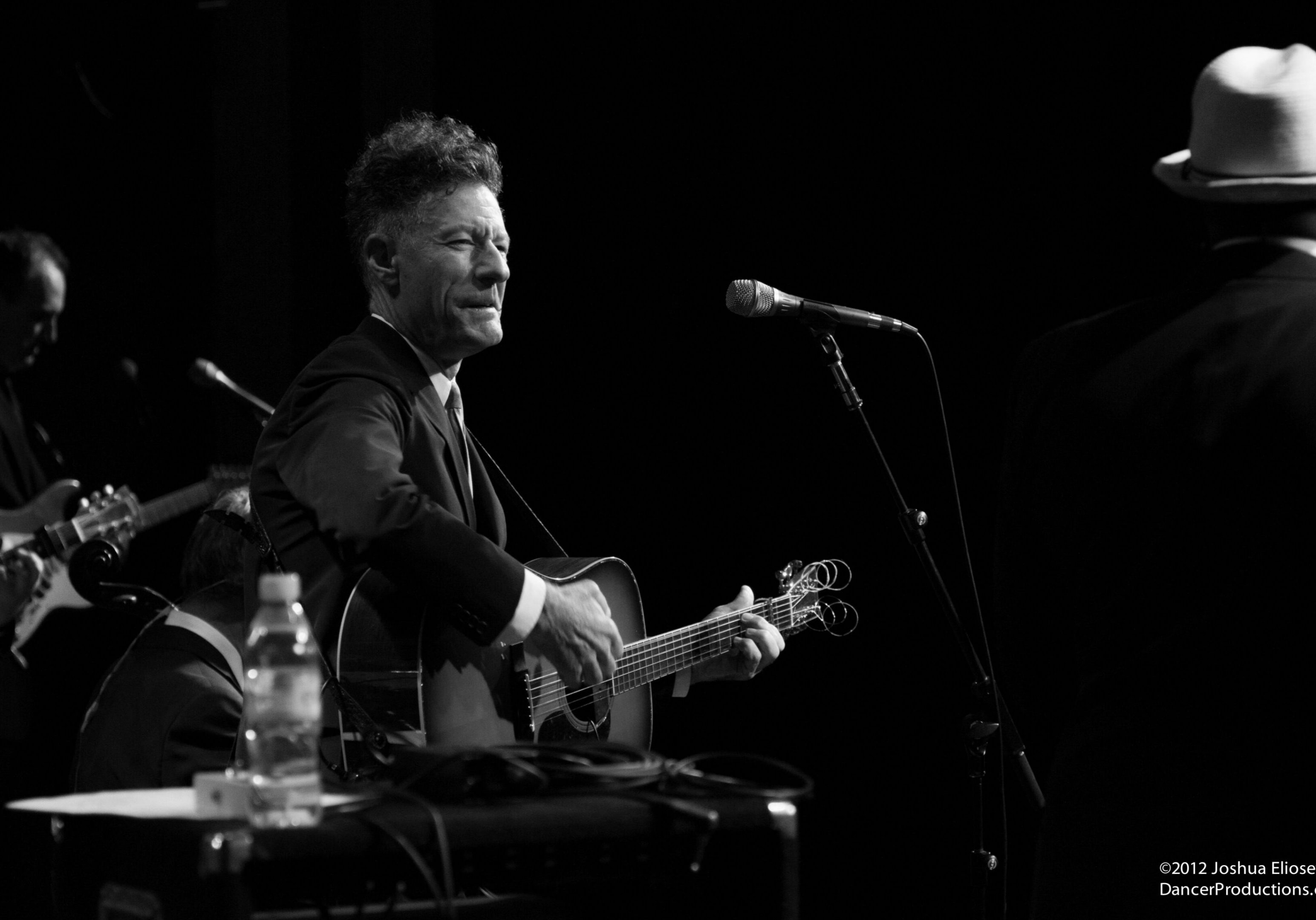 Man playing guitar on stage, black and white.