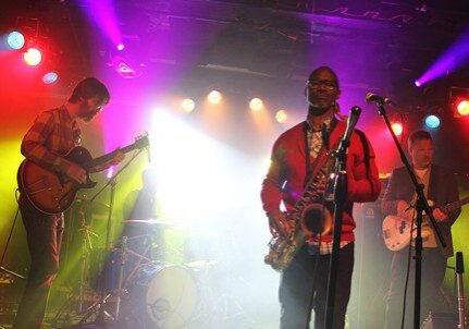 Band performing on stage with colorful lights.