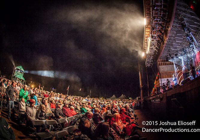 Outdoor concert with large seated audience.