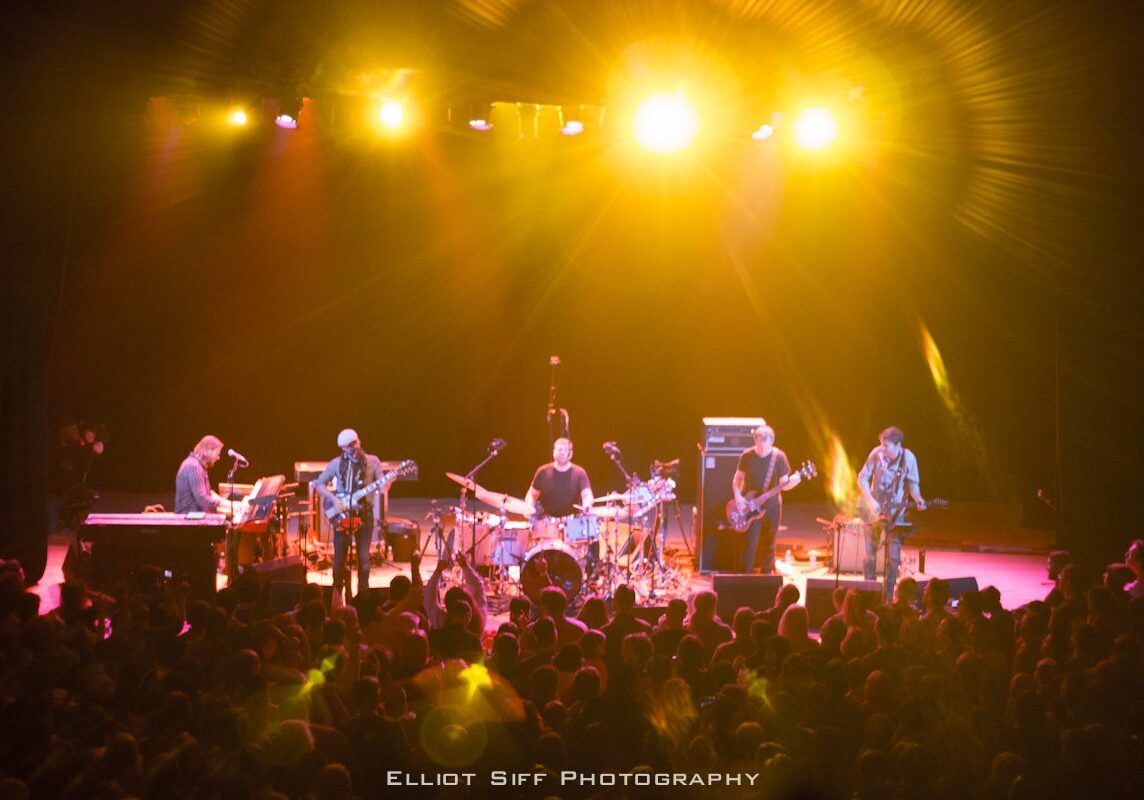 Band performing on stage with audience.