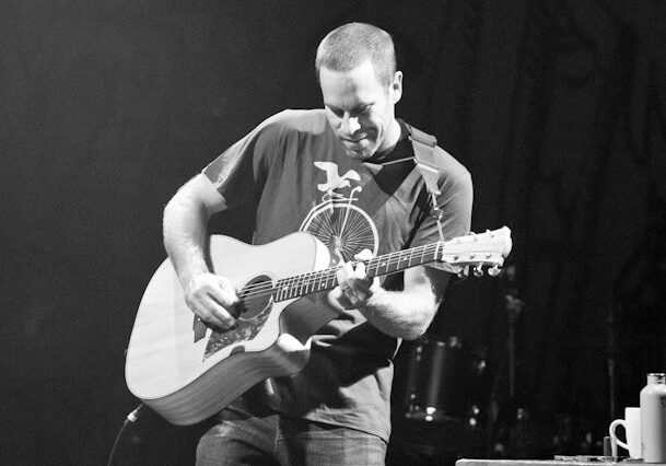 Man playing acoustic guitar on stage.