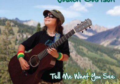 Young musician with guitar in scenic mountains.