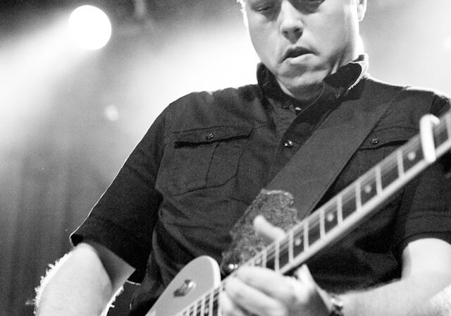 Guitarist playing electric guitar on stage.