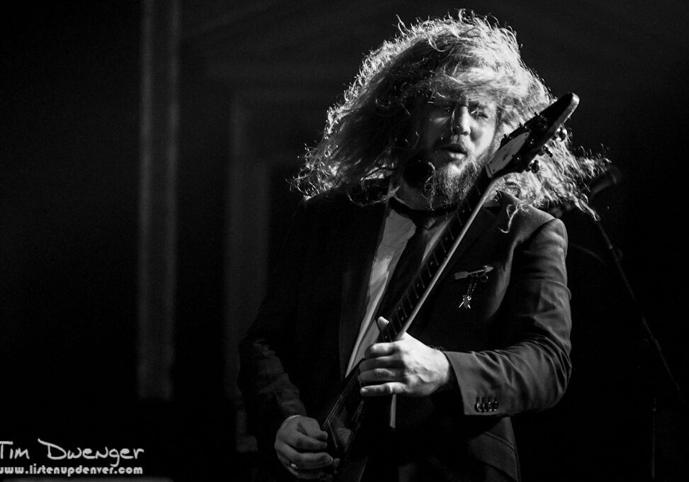 Musician passionately playing guitar on stage.