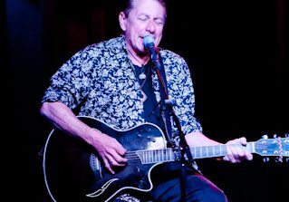 Musician performing with guitar on stage.