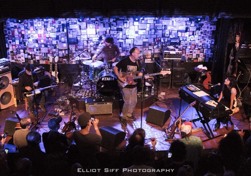 Band performing on stage with audience watching.