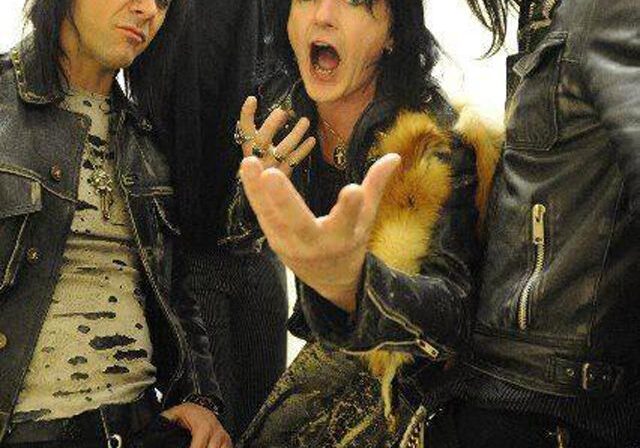 Rock band posing energetically in leather jackets.