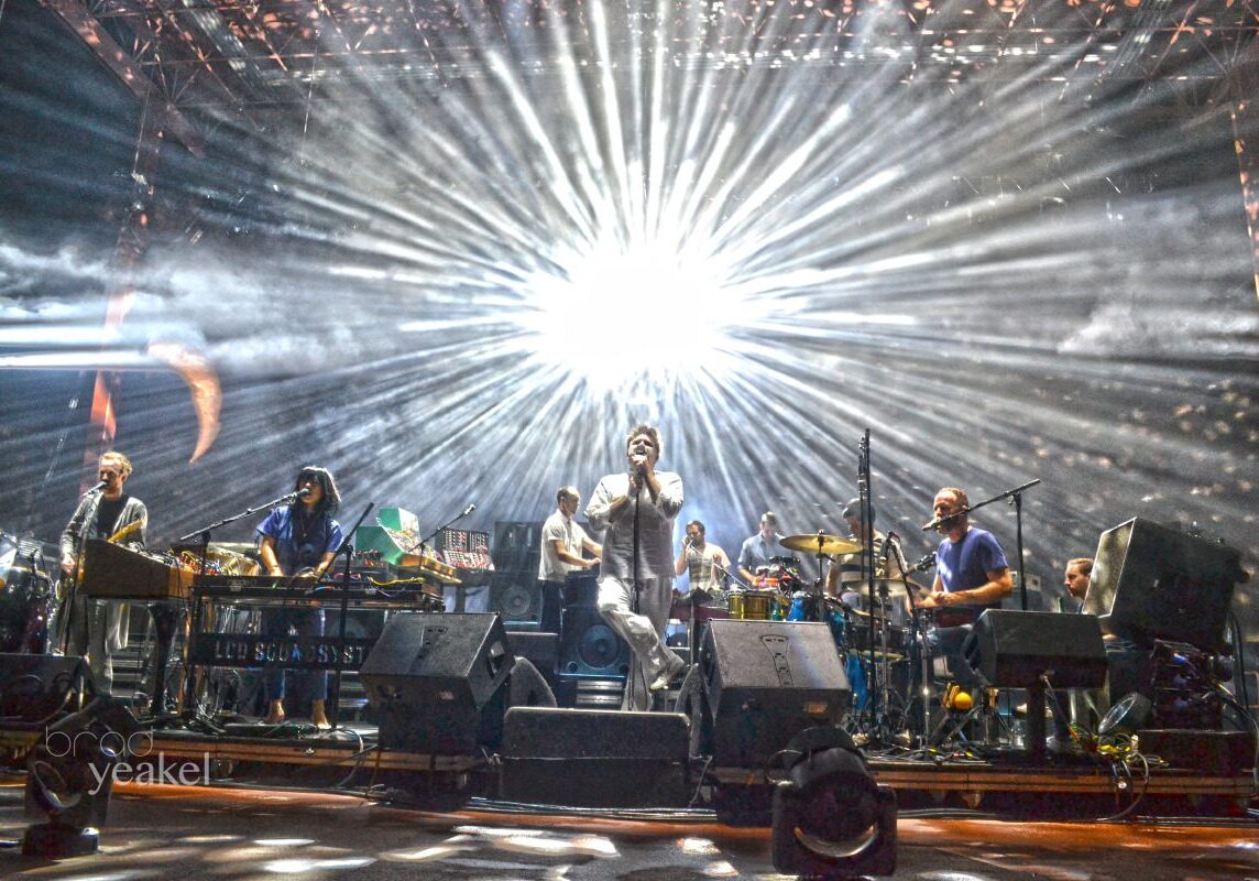 Band performing on stage with bright lights.