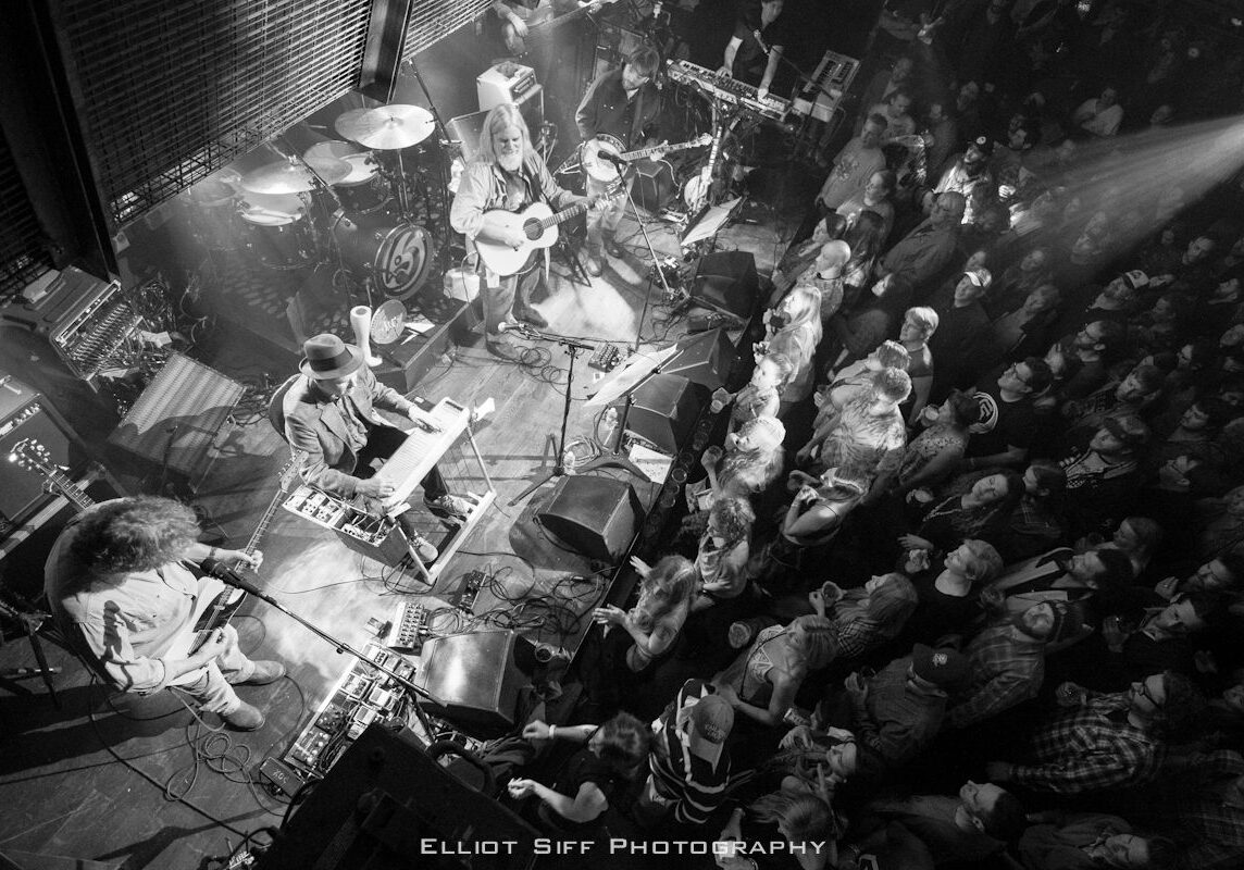 Band performing live on stage with crowd.