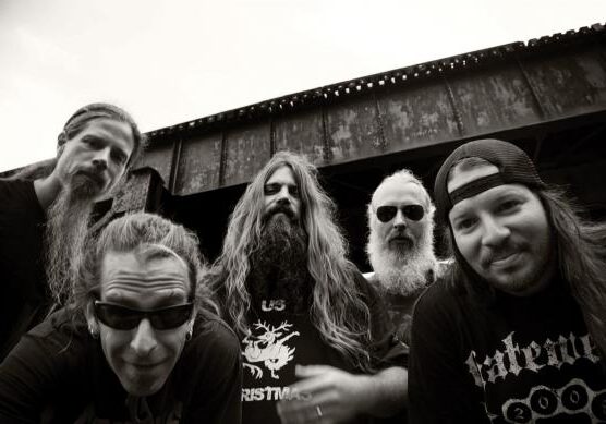 Five men with long hair, beards outdoors.