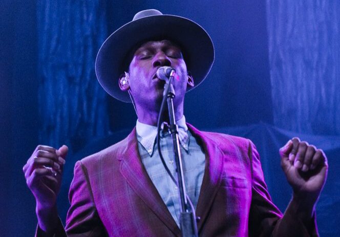 Singer in a hat performing on stage.