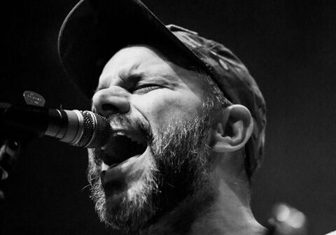 Singer passionately performing on stage, black and white.