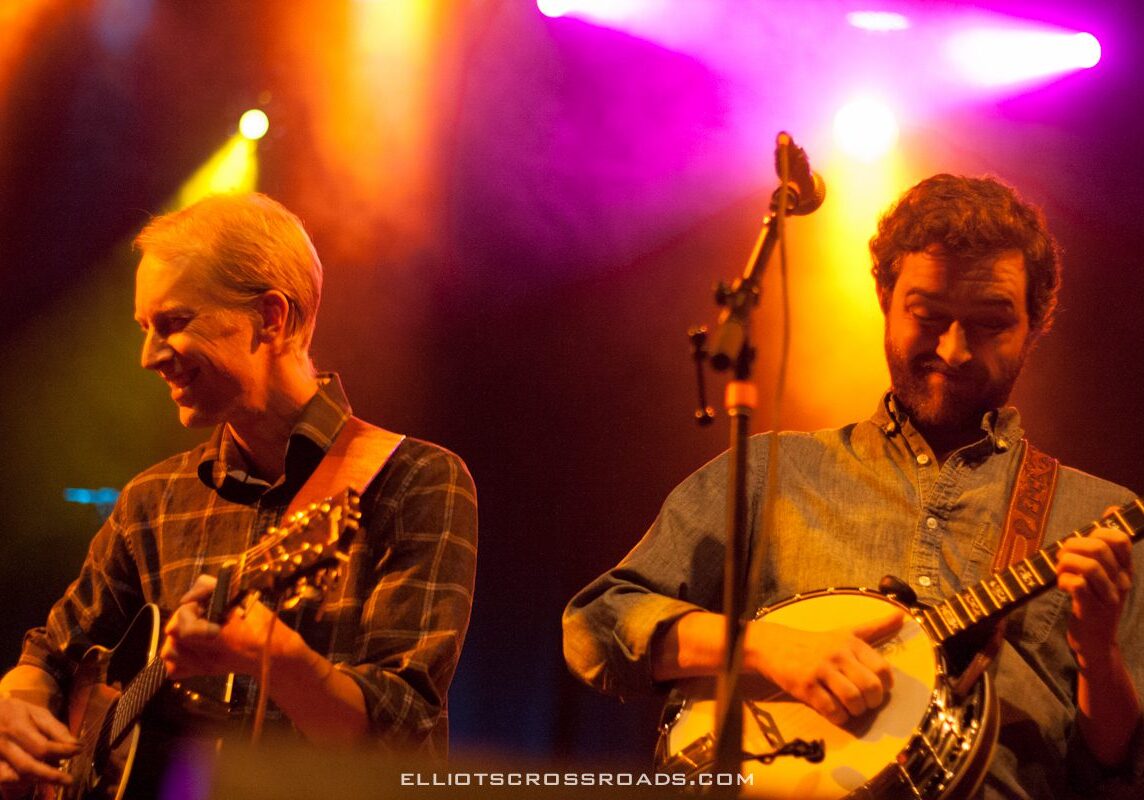 Two musicians playing guitars on stage.