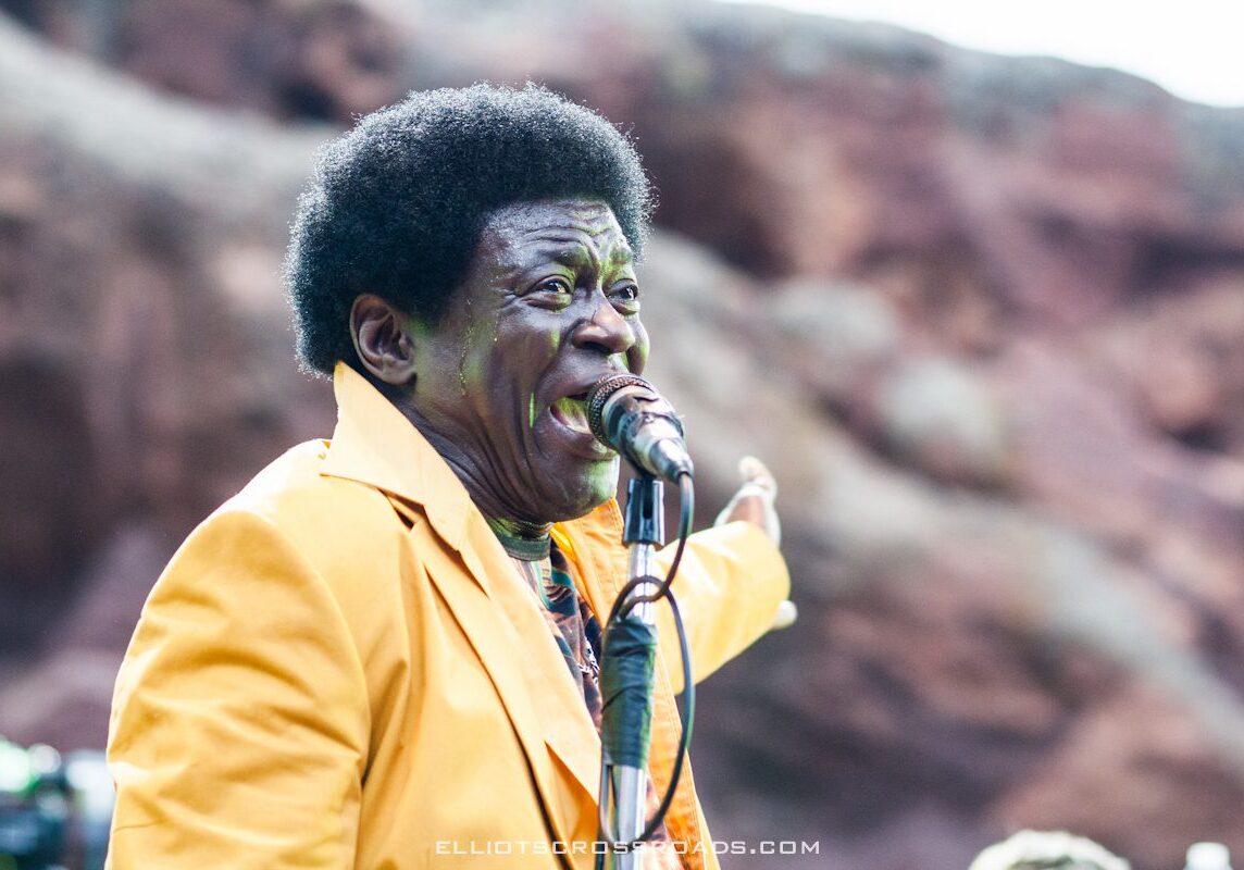 Singer performing outdoors in yellow suit.