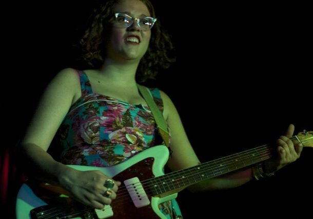 Person playing electric guitar on stage.