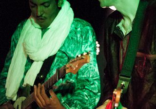 Two musicians playing guitars on stage.