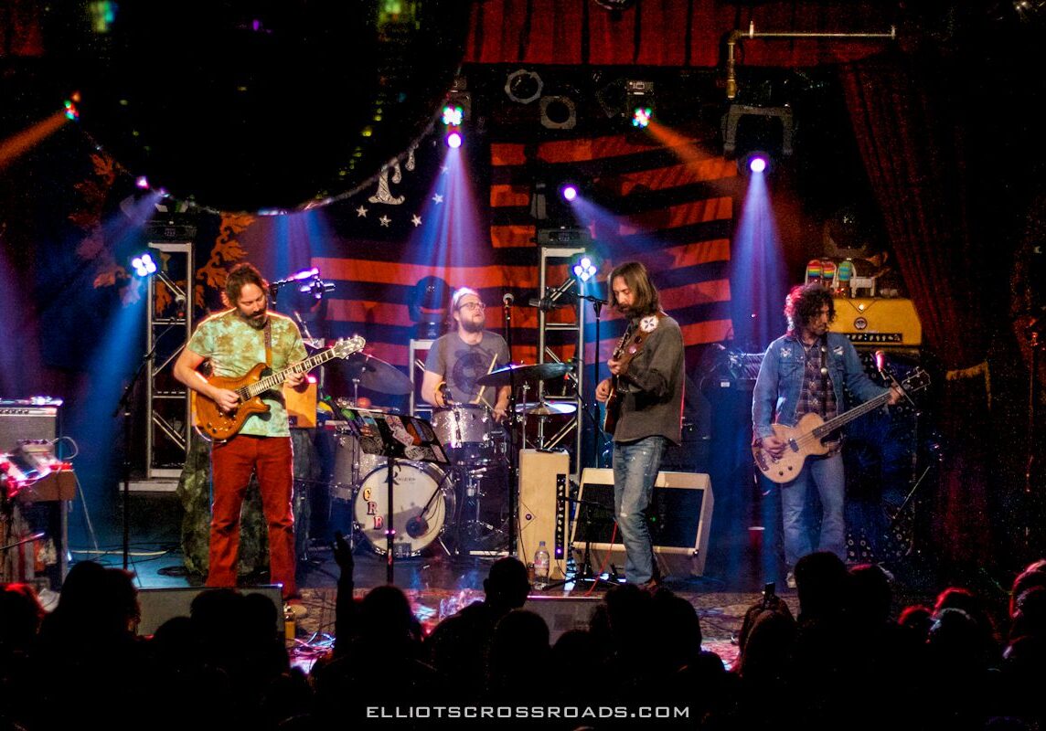 Band performing live on stage with lights.