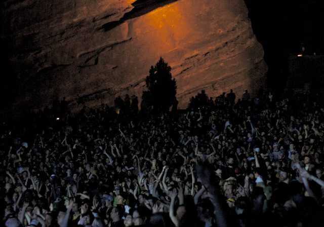 Concert crowd under illuminated rock formation.