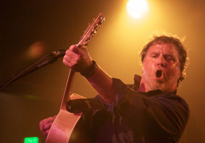 Musician performing energetically with a guitar.