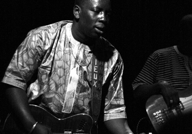Musician playing electric guitar on stage.
