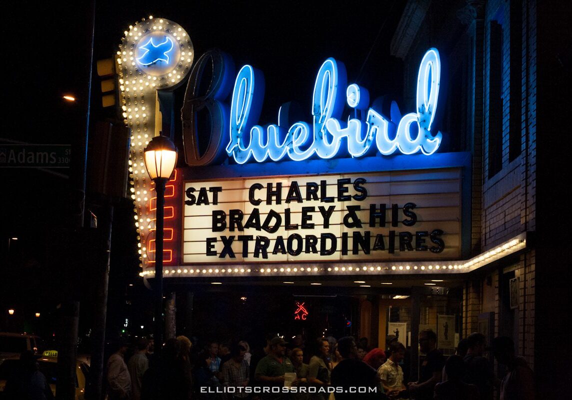 Bluebird Theater marquee at night with crowd.
