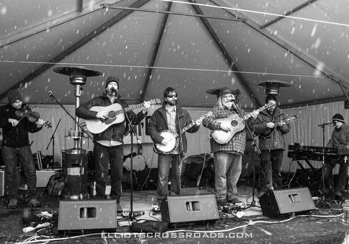 Band performing on outdoor stage in snow.