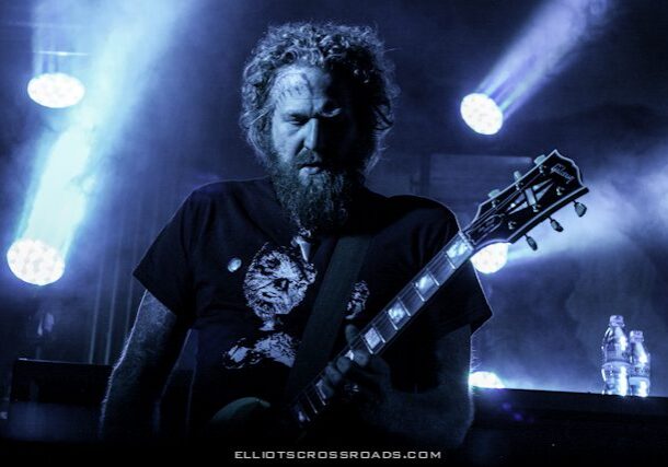 Musician playing guitar on stage with lights.