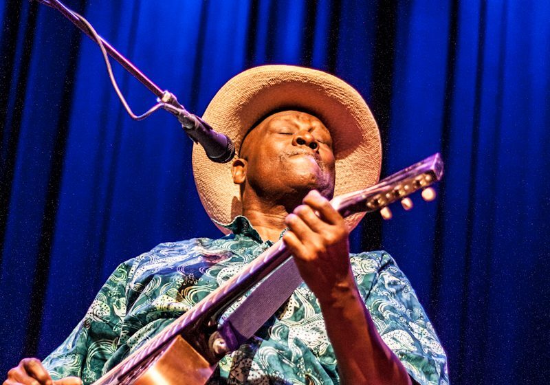 Musician performing with guitar on stage.