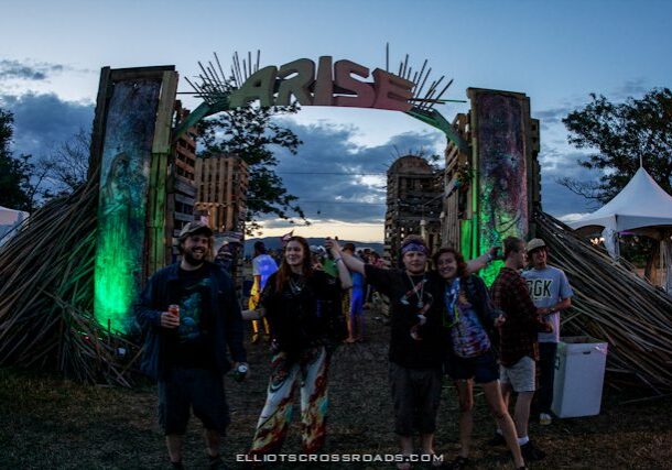Festival entrance with people under evening sky.